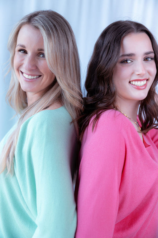 Zwei Frauen in mint- und pinkfarbenen Strickpullovern