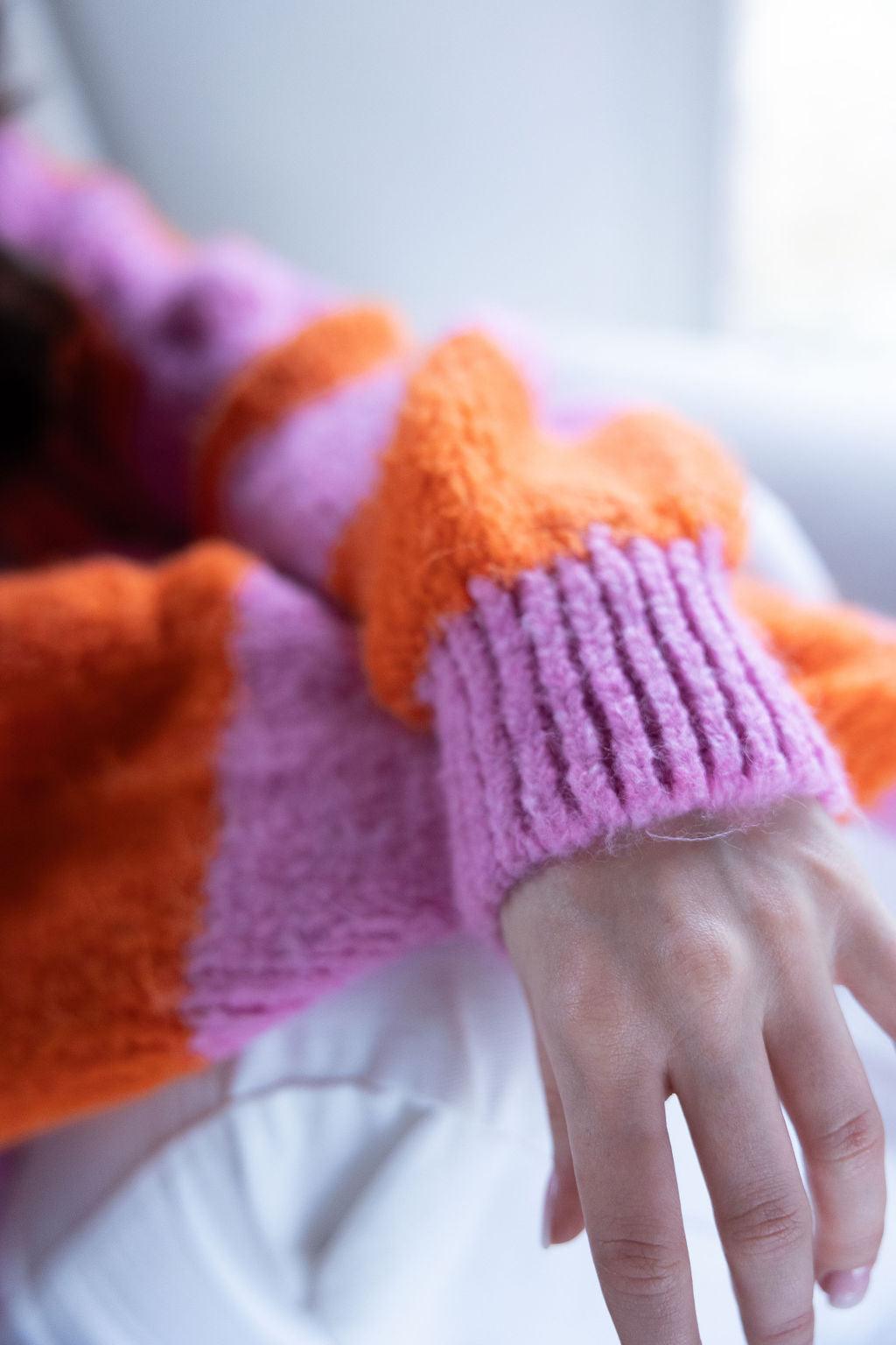 Detailaufnahme orange-pinker Strickpullover-Ärmel