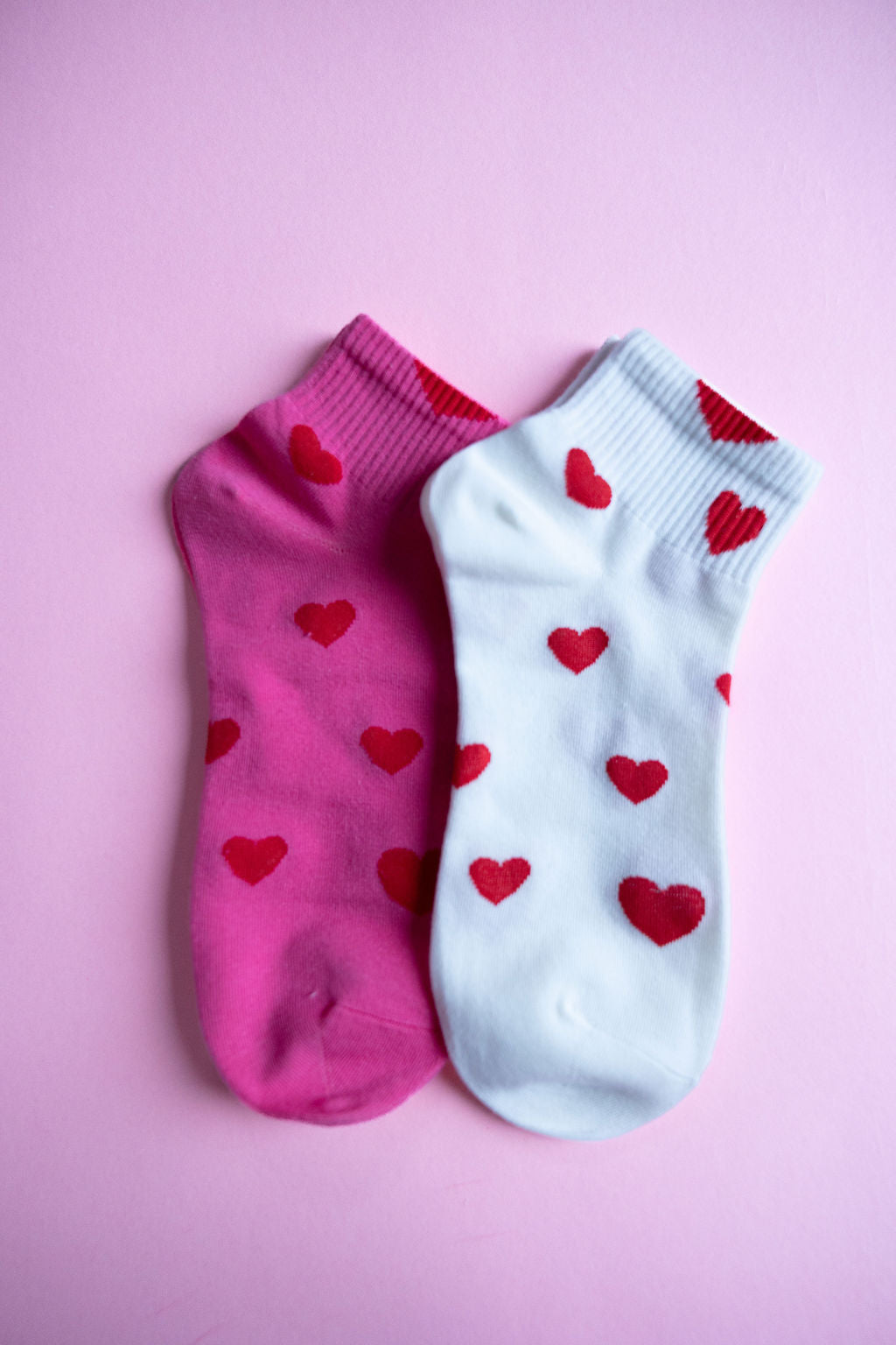 Zwei Paar Damen-Socken mit Herzmuster in Weiß und Pink auf rosa Untergrund