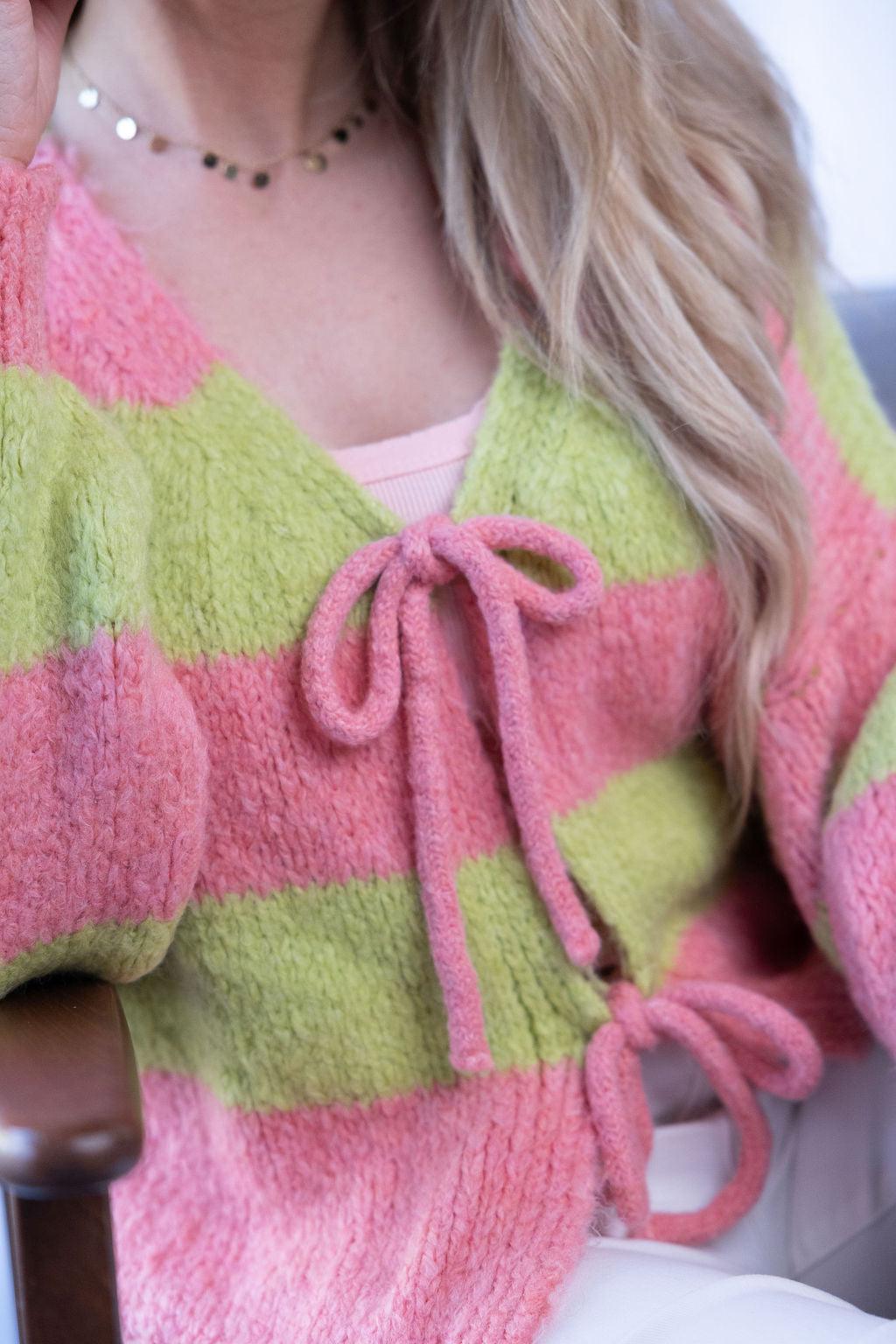 Pink-grüner Strickpullover mit Schleifendetail in Nahaufnahme
